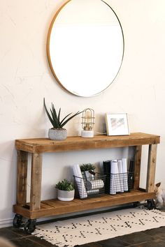 a wooden shelf with plants and pictures on it next to a round mirror above the table