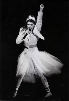 a black and white photo of a woman in a tutu skirt with her arms up