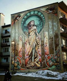 a large mural on the side of a building with a woman standing next to it