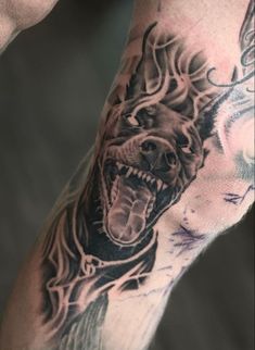 a man with a tattoo on his arm has a wolf head and flames coming out of it