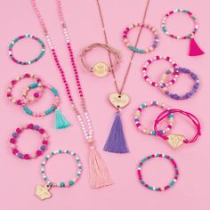 a collection of bracelets and necklaces on a pink background with the word love spelled in gold