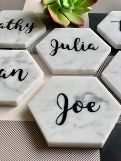 marble coasters with names on them sitting on a table next to a succulent