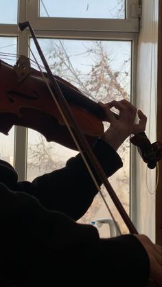 a person playing the violin in front of a window