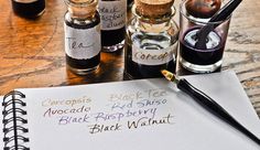 an open notebook with writing on it next to some bottles filled with ink and pens