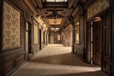 an empty hallway with wooden paneling and ornate wallpaper