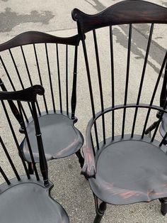 two black chairs sitting next to each other on top of a cement floor covered ground