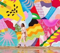 a woman standing in front of a colorful wall