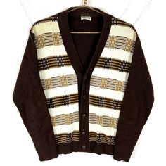 a brown and white cardigan sweater hanging on a clothes hanger next to a wall