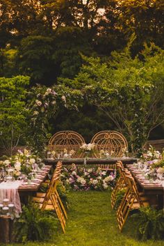 an outdoor dinner table set up with flowers and greenery