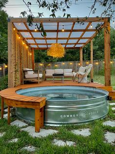 a hot tub in the middle of a yard with lights hanging from it's roof