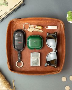 a wooden tray with sunglasses, keys and other items