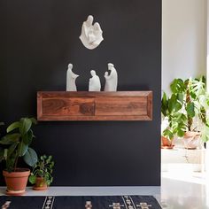 a living room with black walls and plants on the shelf next to the fireplace mantel