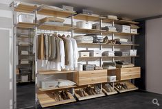 an organized closet with clothes and shoes on shelving units in the center, along with other storage bins