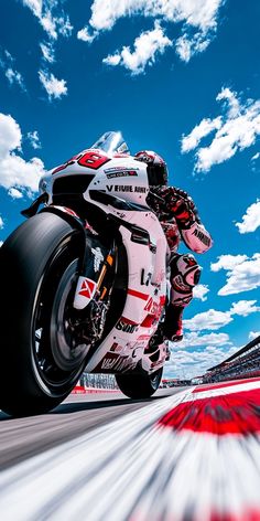 a man riding a motorcycle on top of a race track under a cloudy blue sky