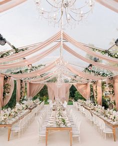 an outdoor dining area with tables, chairs and chandeliers set up for a formal function