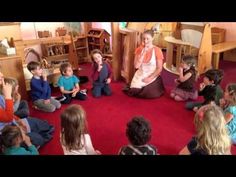 a group of children sitting on the floor in front of a woman