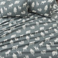 a bed covered in grey and white moose print sheets