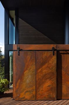 an open sliding door on the outside of a house with wood flooring and black siding