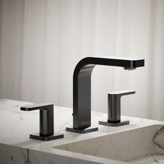 two black faucets sitting next to each other on a marble counter top in front of a curtained window