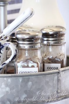 jars and spoons are sitting in a metal container with labels on the bottom that read cinnamon