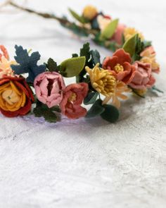 a flower crown made out of felt flowers on top of a white cloth tablecloth