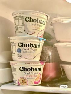 three yogurts are stacked on top of each other in the refrigerator with plastic containers