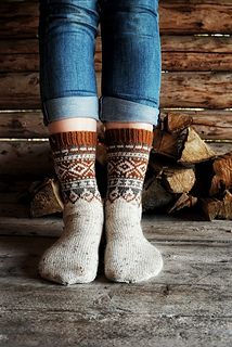 the legs of a woman wearing socks and jeans standing in front of firewood logs