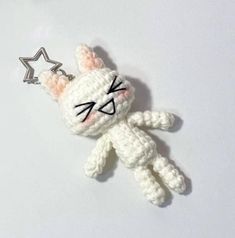 a crocheted keychain with a cat on it's side and a star in the middle