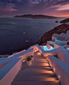 stairs leading up to the top of a building with lights on them and water in the background