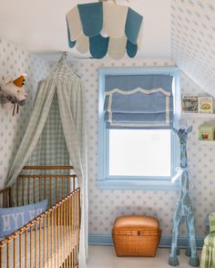 a baby's room with blue and white wallpaper, a crib, and a window