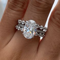 a woman's hand with a diamond ring on top of her finger and the other hand holding an engagement ring