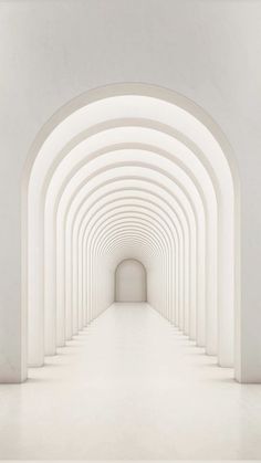 an empty tunnel with white walls and arches leading into the light at the end,