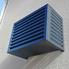 an air conditioner mounted to the side of a building with blue shutters on it