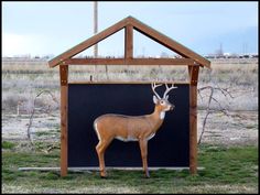 a statue of a deer in front of a small building with a roof on top