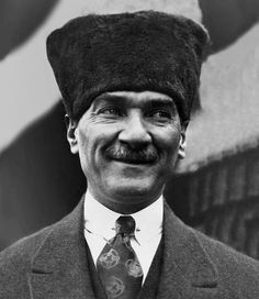 black and white photograph of a man with a mustache wearing a fur hat, tie and jacket