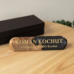 a wooden box sitting on top of a table next to a black box with the word roman kochut