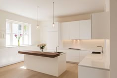 an empty kitchen with white cabinets and wood counter tops is seen in this image, there are flowers on the island