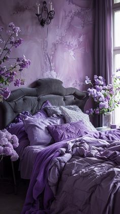 a bed with purple comforters and pillows in front of a window filled with flowers