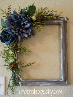 an old frame is decorated with blue flowers and greenery for a rustic touch to any room