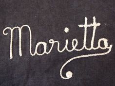 the word marietta written in white ink on a black shirt with an embroidered design