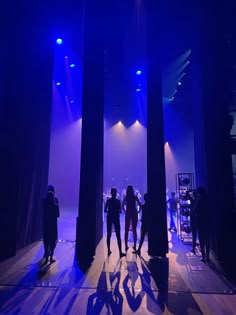 several people are standing in the middle of a stage with blue lights and purple lighting