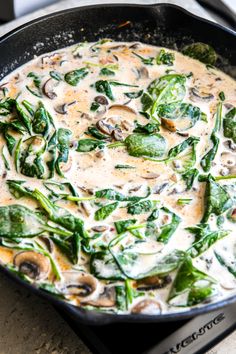 a pan filled with mushrooms and spinach on top of a stove