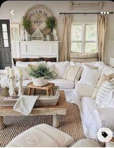 a living room filled with lots of white furniture and pillows on top of a rug