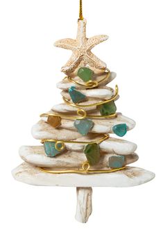 a ceramic christmas tree ornament hanging from a starfish on a white background