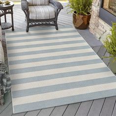 a blue and white striped rug sitting on top of a wooden floor next to a chair