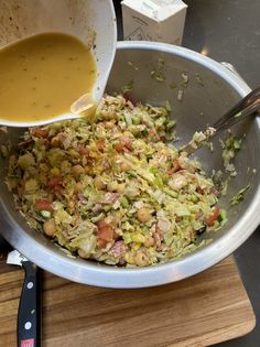 a bowl filled with food next to a knife and some sauce on top of a cutting board