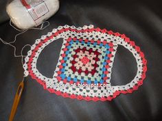 a close up of a crocheted object on a table with scissors and thread