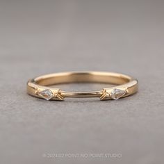 a gold ring with two small diamonds on it's side, sitting on a gray surface