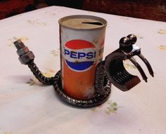 an old pepsi can sitting on top of a table next to a metal phone holder