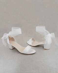 the bride's white shoes are adorned with a satin ribbon and bowknots